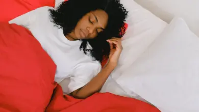 Mulher dormindo de lado na cama, com a cabeça apoiada no travesseiro